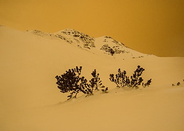 Blick auf einen schneebdeckten Hügel, der rötlich gefärbt ist