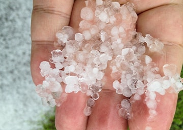 Kleine Eiskörner liegen auf einer geöffneten Hand