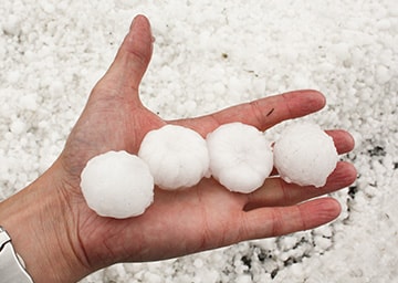 Golfball große Hagelkörner die auf einer Hand liegen