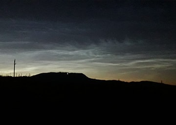 Blick in den Nachthimmel, auf dem leuchtende Wolken erkennbar sind